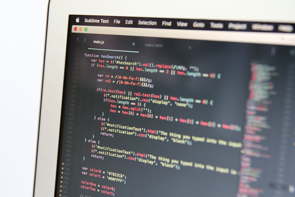 A close-up shot of a computer screen displaying lines of code in a text editor, with a dark background and syntax highlighting in various colors such as red, yellow, and blue. The code appears to be J